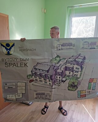 Místostarosta ukazuje banner se zamítnutým návrhem domova pro seniory
